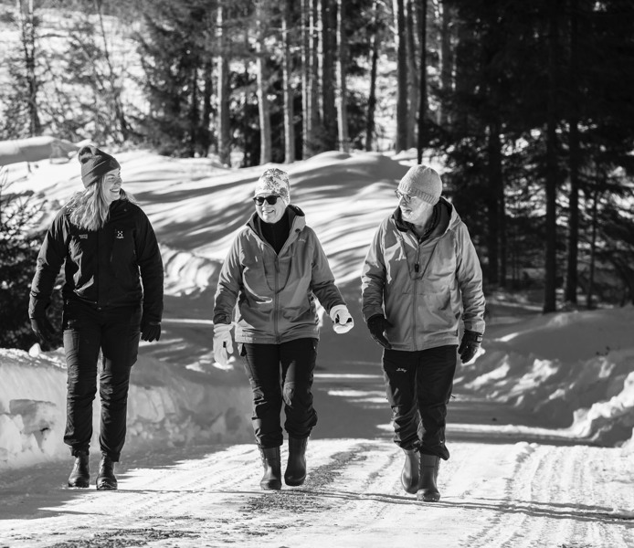 Tre personer går längs en väg på vintern.